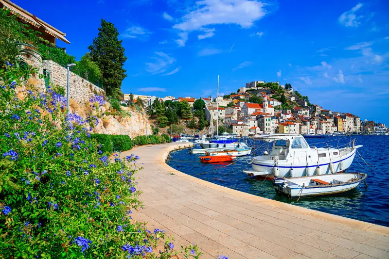 Küstenpromenade Šibenik mit Booten
Malerische Uferpromenade von Šibenik mit kleinen Booten, mediterranen Häusern und kristallklarem Wasser – perfekte Kulisse für entspannten Segelurlaub an der kroatischen Adriaküste.